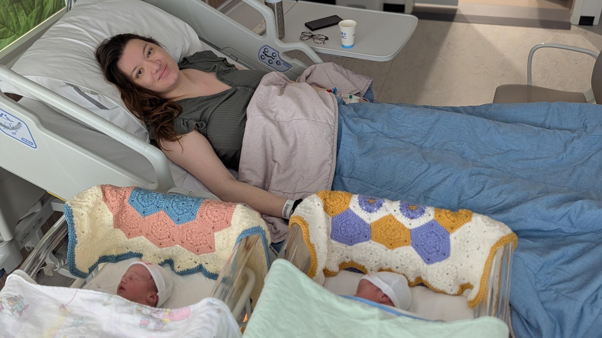 Mama in het ziekenhuisbed met Viola en Melody in hun mandjes ernaast, ingestopt onder gehaakte dekentjes.